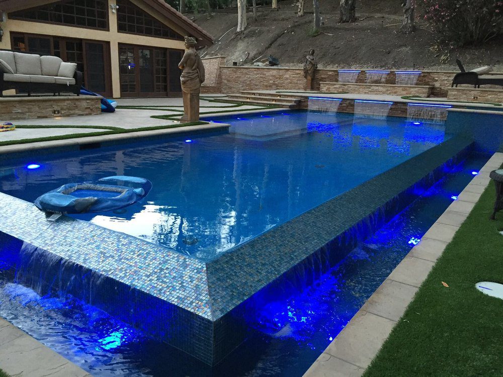 a luxury blue pool with overflow and small tile detail