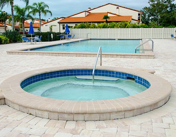 A paved patio with hot tub and swimming pool